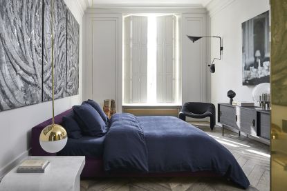 Best mattress hero image: a luxury bedroom with a purple bed and statement lighting